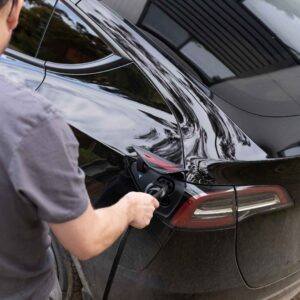 man connecting black tesla car to charge