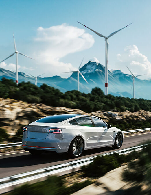 Electric vehicle driving on a scenic road surrounded by wind turbines, symbolizing sustainable energy and EV charging infrastructure.