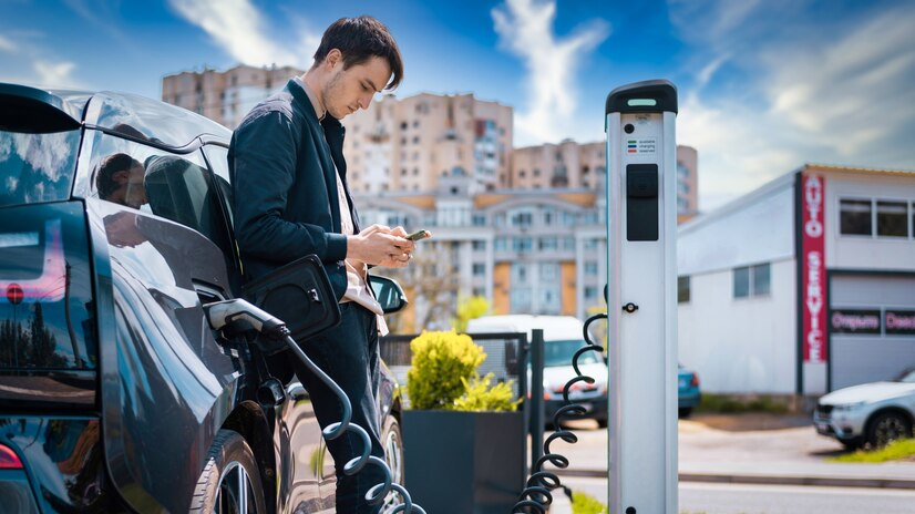 Man resting beside a public EV charging station.